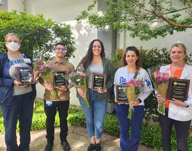 Employees holding awards and flowers outdoors