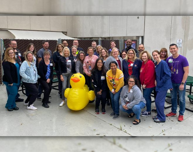 Large group posing outdoors with inflatable duck