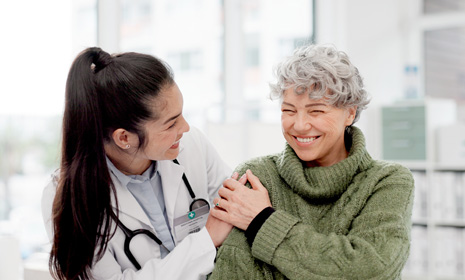 Healthcare provider supporting seated older patient
