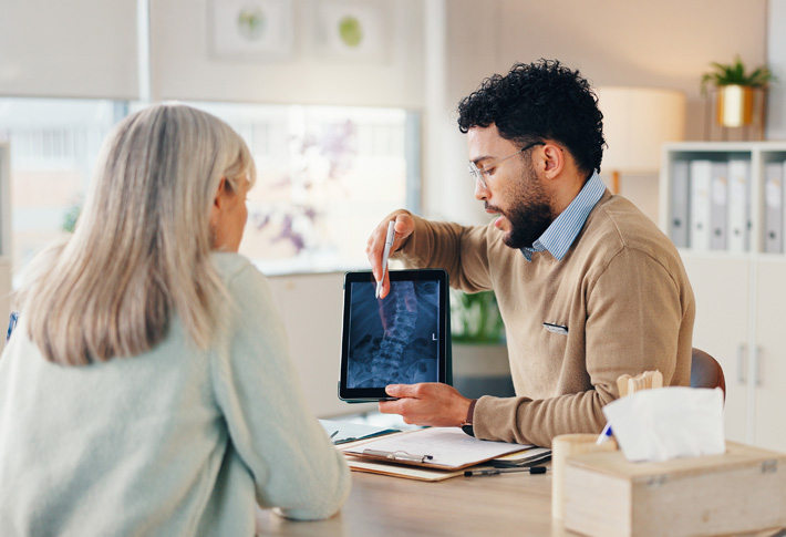 A doctor holds a tablet computer and discusses medical care options with a patient